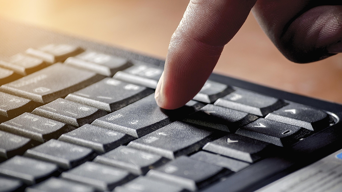 Eine Hand über einer Computertastatur